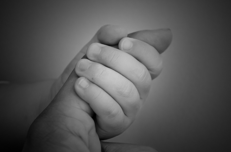 a baby grips its mother's finger