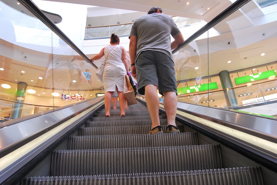 shoppers ride an escalator as it ascends