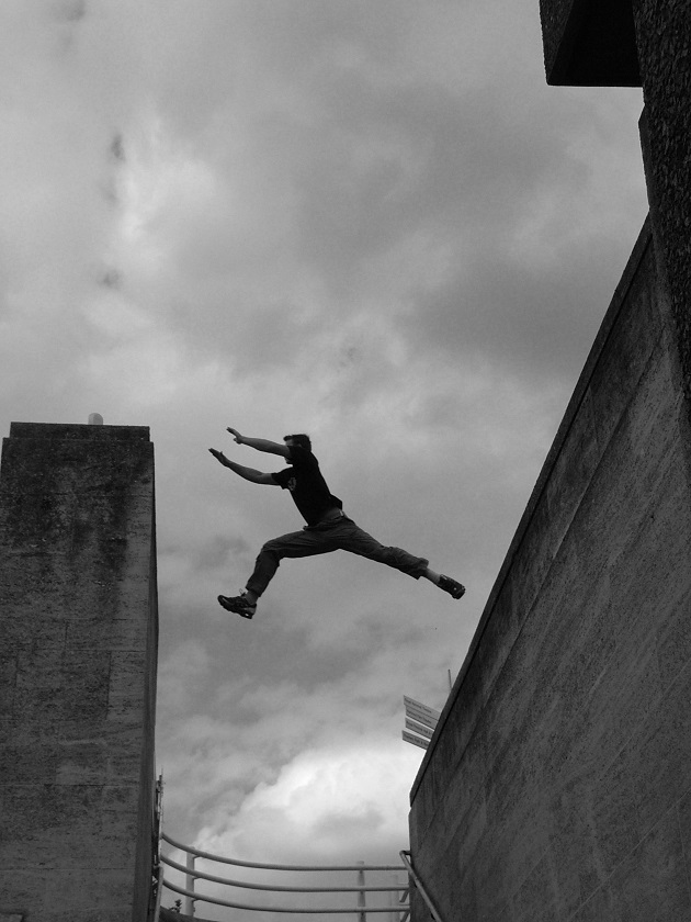 a freerunner jumps over a large gap