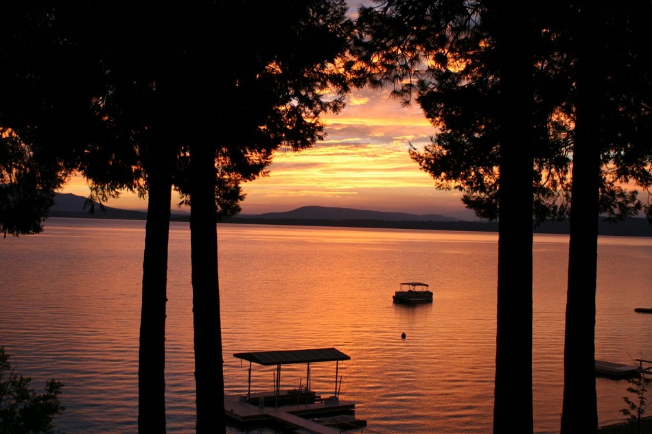 a vibrant sunset on a lake between the trees
