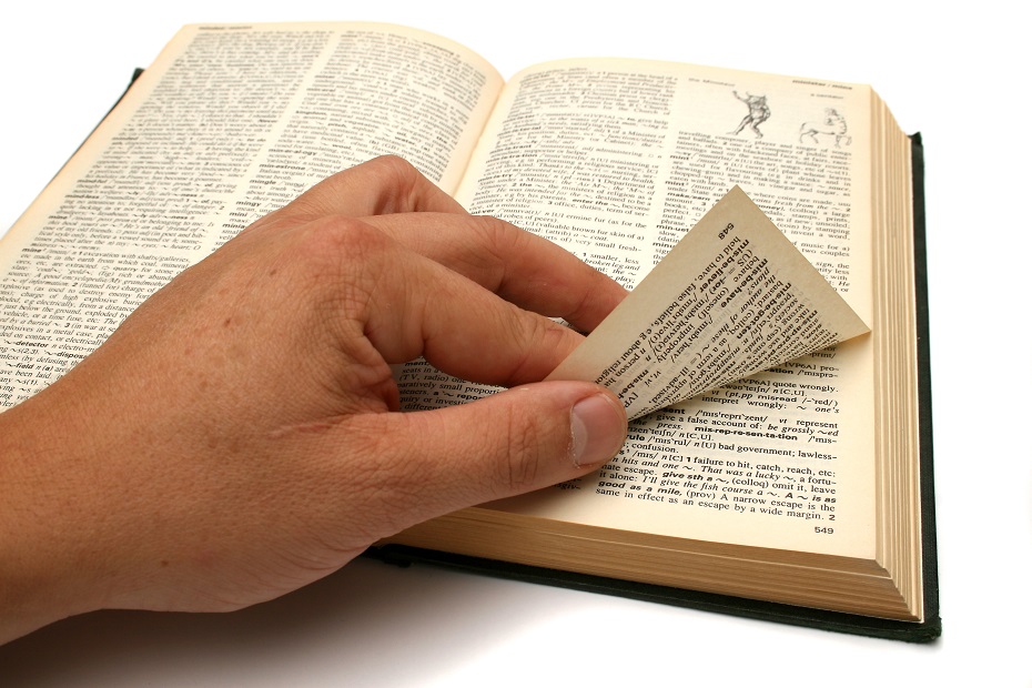 a hand peels up the corner of a dictionary page
