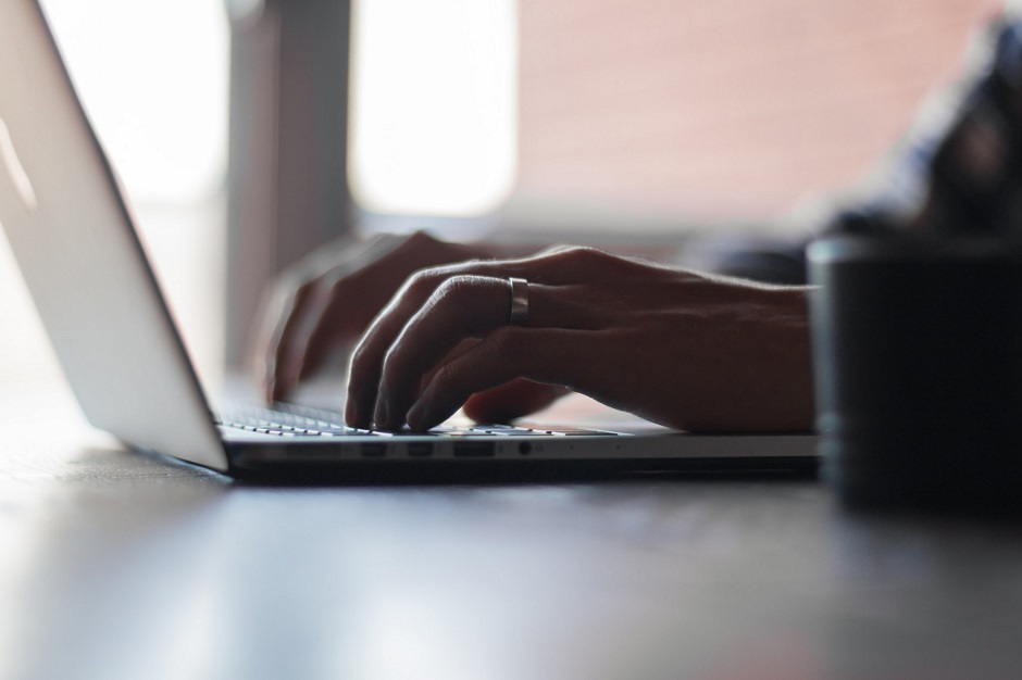 hands typing on a silver laptop