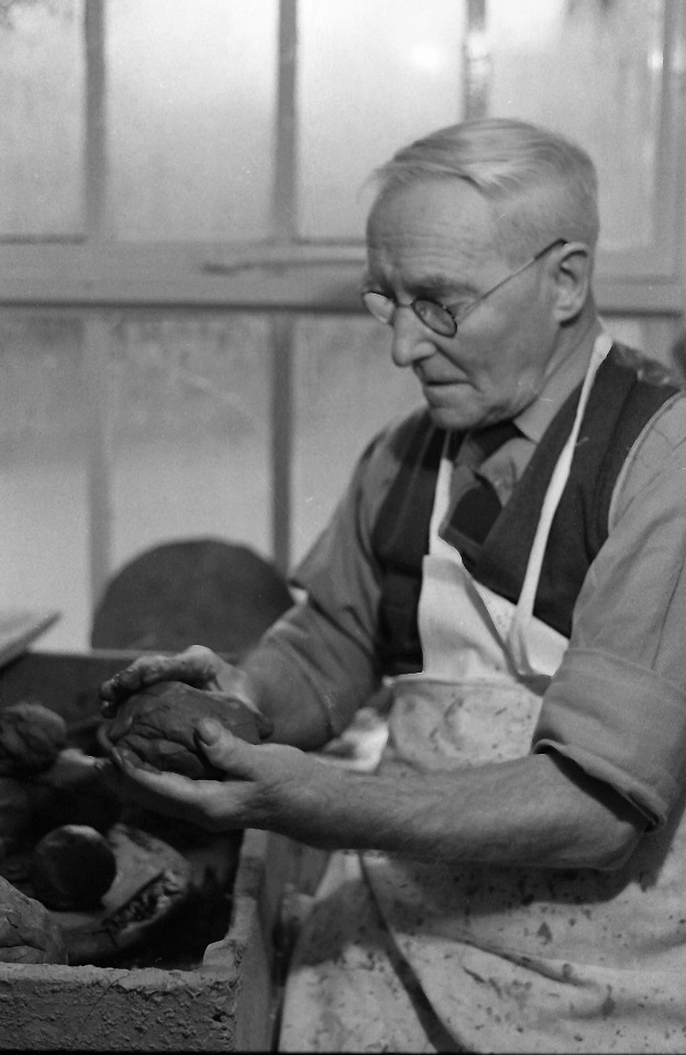 an old man works on a piece of pottery